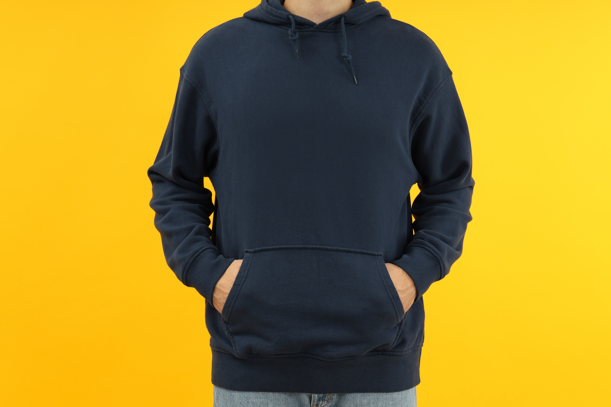 Man in Hoodie with Hands in Pocket on Yellow Background